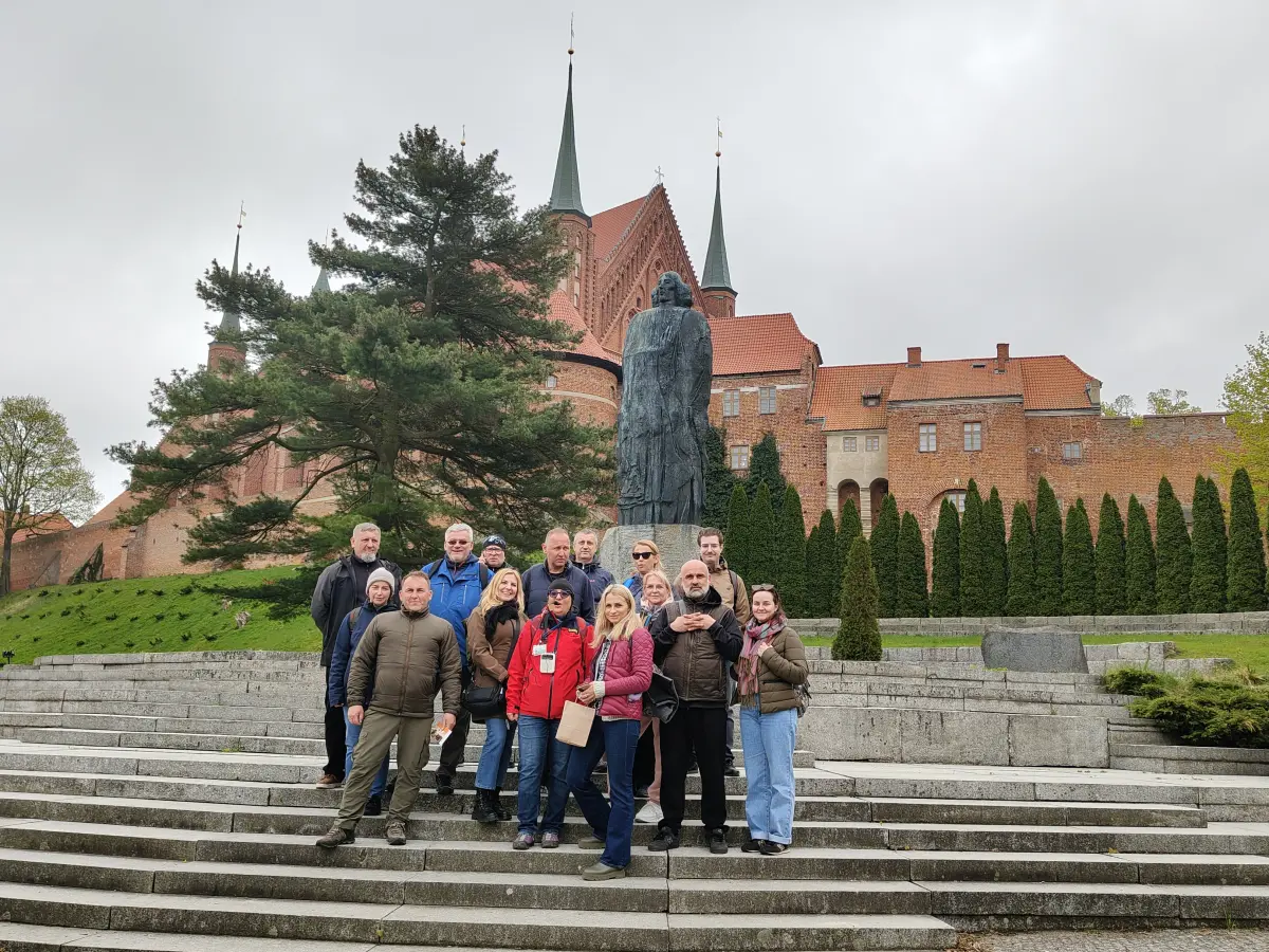 Turyści z przewodnikiem po Frpomborku pod pomnikiem Kopernika